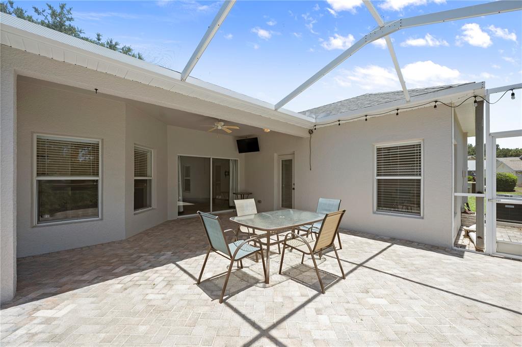 A screened-in patio features a dining set on a paver floor under a roof — 16712 CARACARA COURT, SPRING HILL, FL