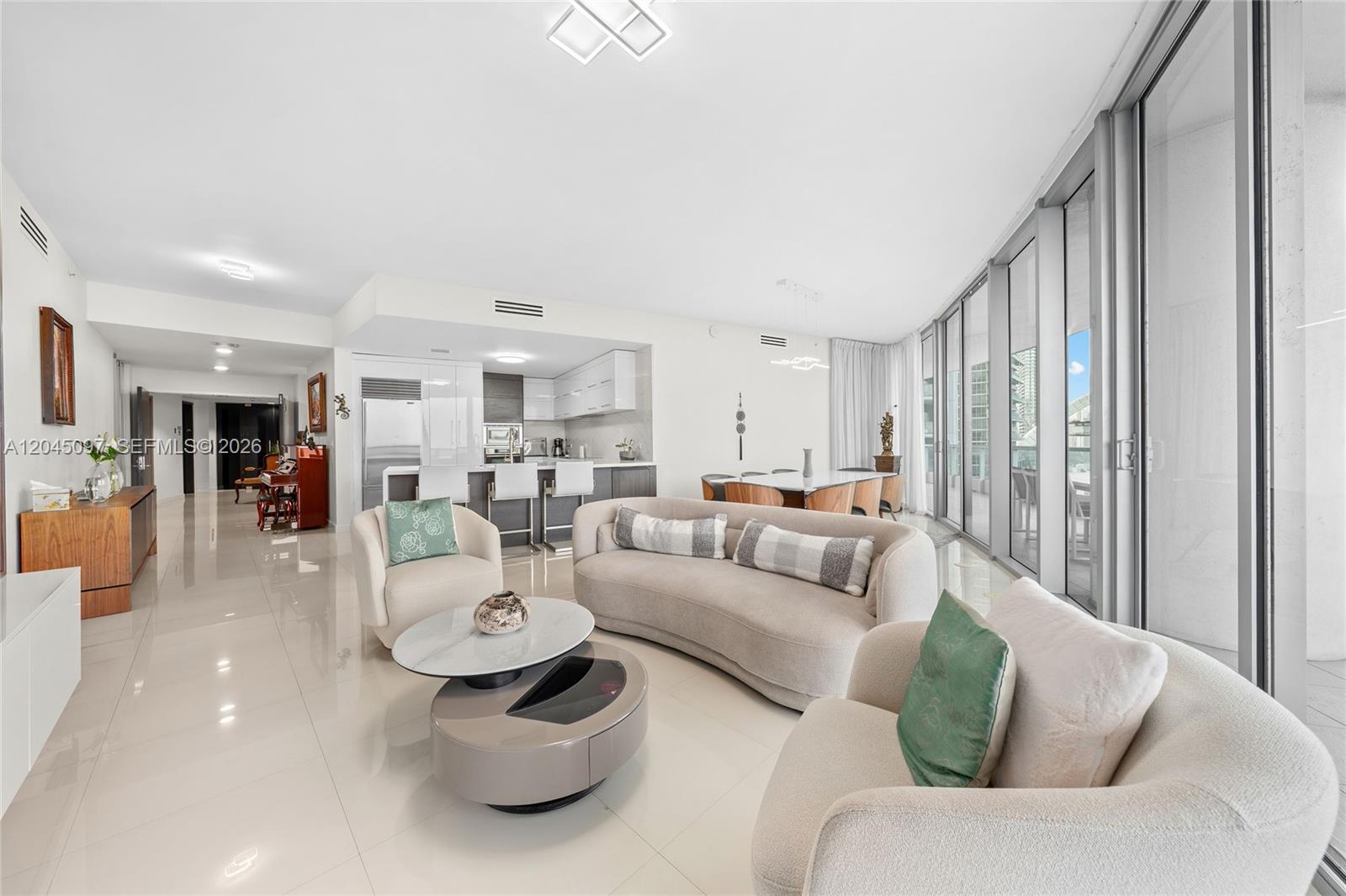 A bright, open-concept living and dining area features white tile floors and floor-to-ceiling windows — 900 Biscayne Blvd # 2506, Miami FL 33132, MIAMI, FL