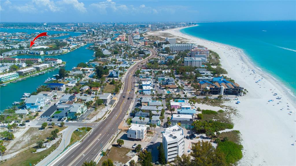 An aerial view shows a coastal town with a beach, a road, and a waterway — 12140 CAPRI CIRCLE S UNIT 709, TREASURE ISLAND, FL