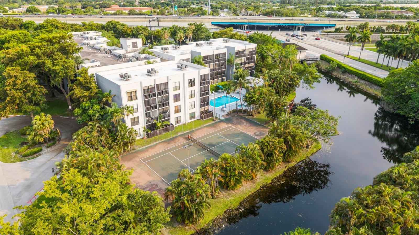 An aerial view shows a multi-story apartment building with a swimming pool and tennis court — 1021 Mockingbird Lane # 211, Plantation FL 33324, PLANTATION, FL