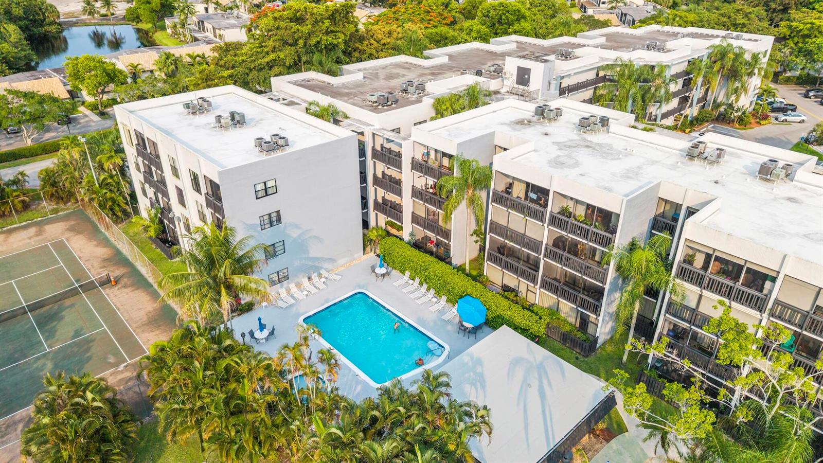 An aerial view shows a multi-story apartment complex with a swimming pool and tennis court — 1021 Mockingbird Lane # 211, Plantation FL 33324, PLANTATION, FL