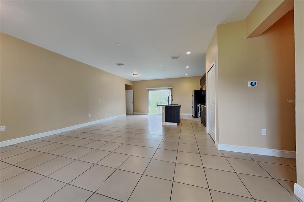 An open-concept living and kitchen area features beige walls, tile flooring, and a kitchen island — 5017 SW 165TH STREET ROAD, OCALA, FL