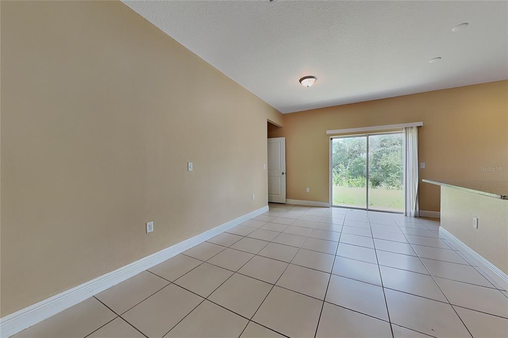 An empty room with tan walls, tiled floors, a sliding glass door, and recessed lighting — 5017 SW 165TH STREET ROAD, OCALA, FL