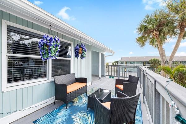 A balcony with wicker furniture and a blue patterned rug overlooks a parking lot — 5043 N BEACH ROAD, ENGLEWOOD, FL