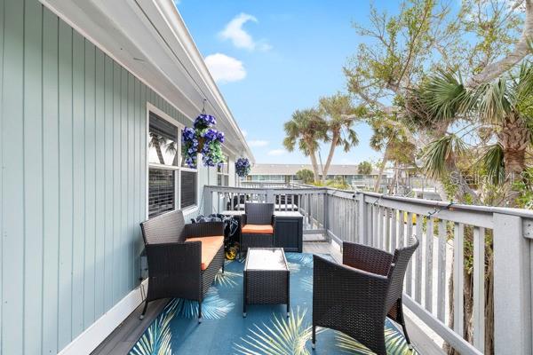 A balcony features wicker patio furniture, a patterned rug, and a light blue exterior wall — 5043 N BEACH ROAD, ENGLEWOOD, FL