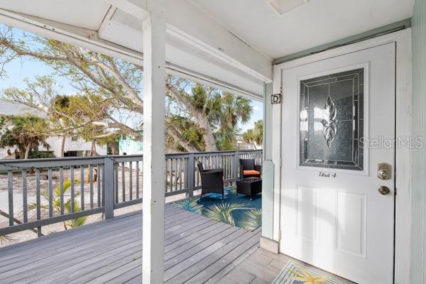 A wooden deck features a white door labeled Unit 4 and a small outdoor seating area — 5043 N BEACH ROAD, ENGLEWOOD, FL