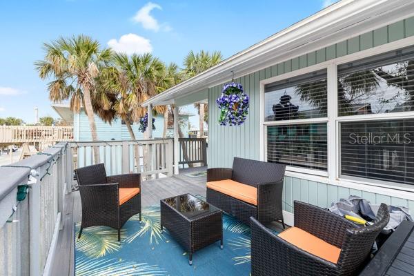 A wooden deck features a wicker patio set with orange cushions and a patterned rug — 5043 N BEACH ROAD, ENGLEWOOD, FL