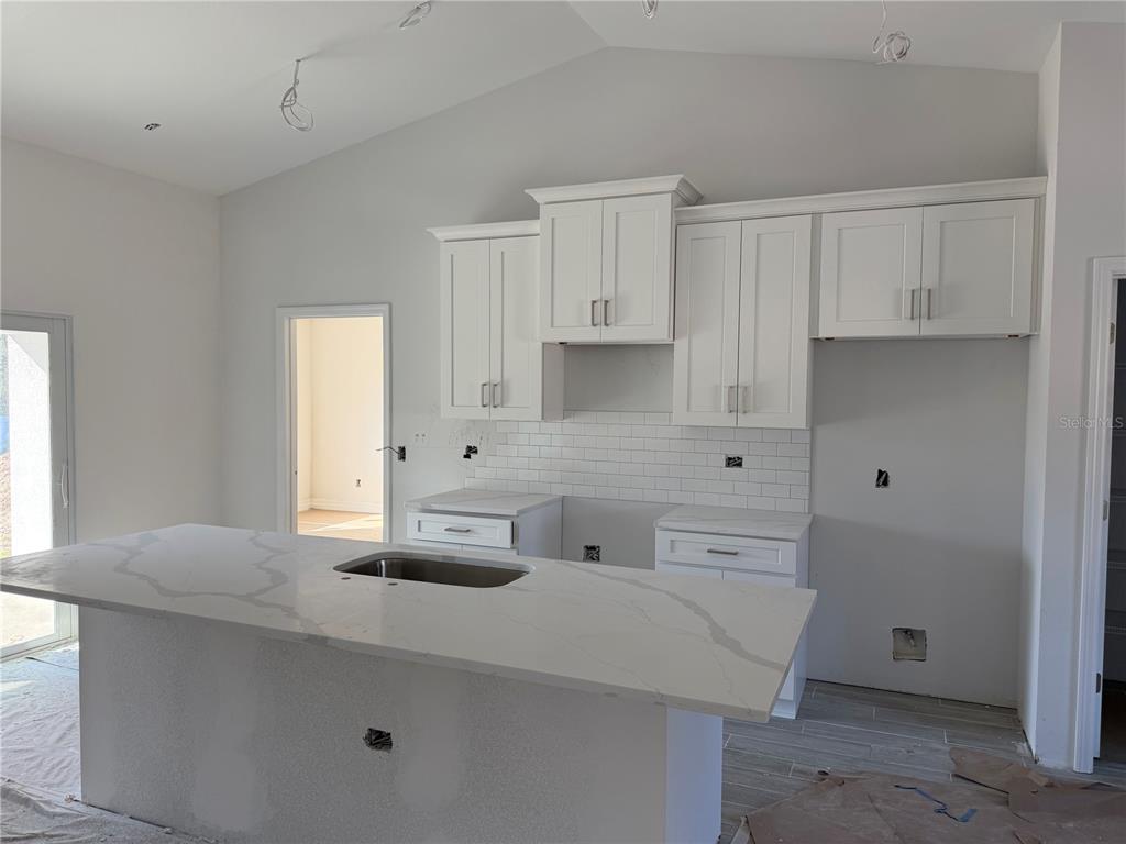 A kitchen features white cabinets, a subway tile backsplash, and a marble-patterned island countertop — 15061 MCGRAW AVENUE, PORT CHARLOTTE, FL