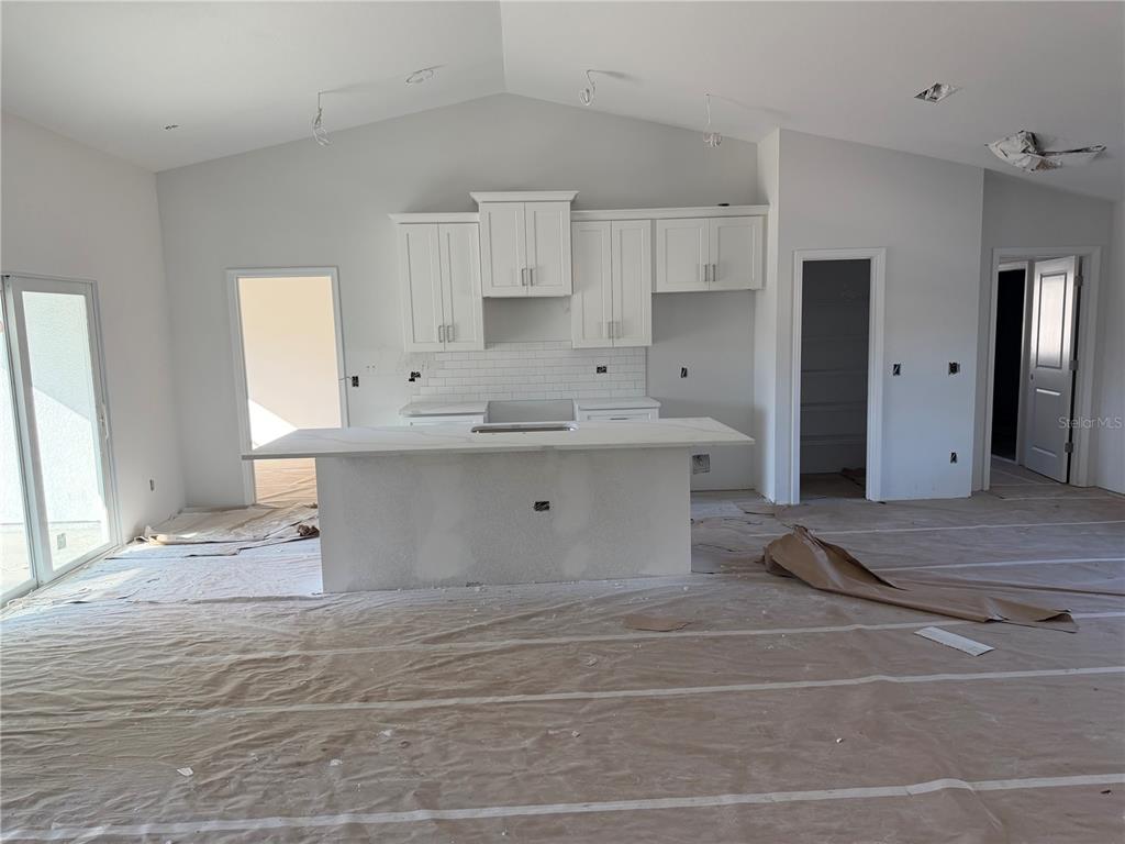 A kitchen under construction features white cabinets, a central island, and a subway tile backsplash — 15061 MCGRAW AVENUE, PORT CHARLOTTE, FL