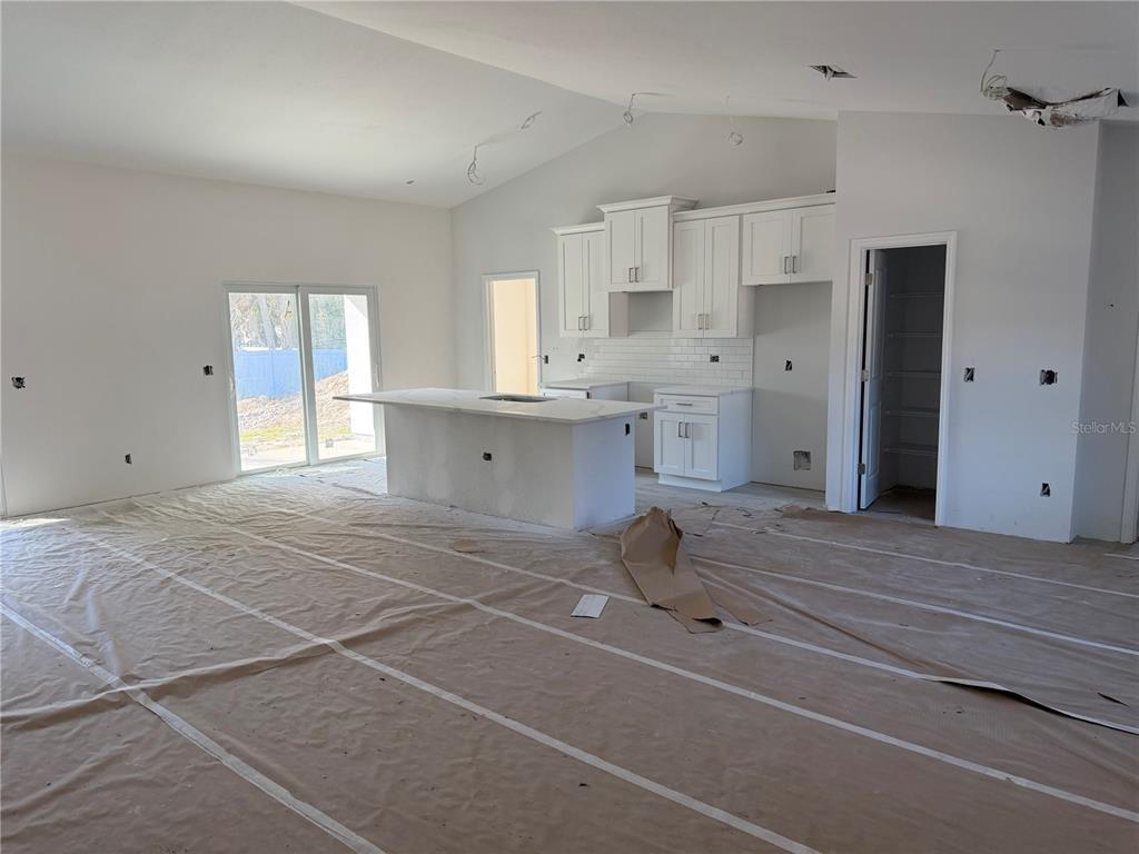 An unfinished kitchen features white cabinets, a central island, and protective paper covering the floor — 15061 MCGRAW AVENUE, PORT CHARLOTTE, FL