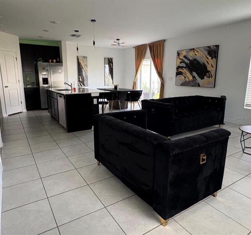 An open-concept living area features black velvet sofas, a kitchen island, and tile flooring — 626 BELL PRAIRIE CIRCLE, LAKE WALES, FL