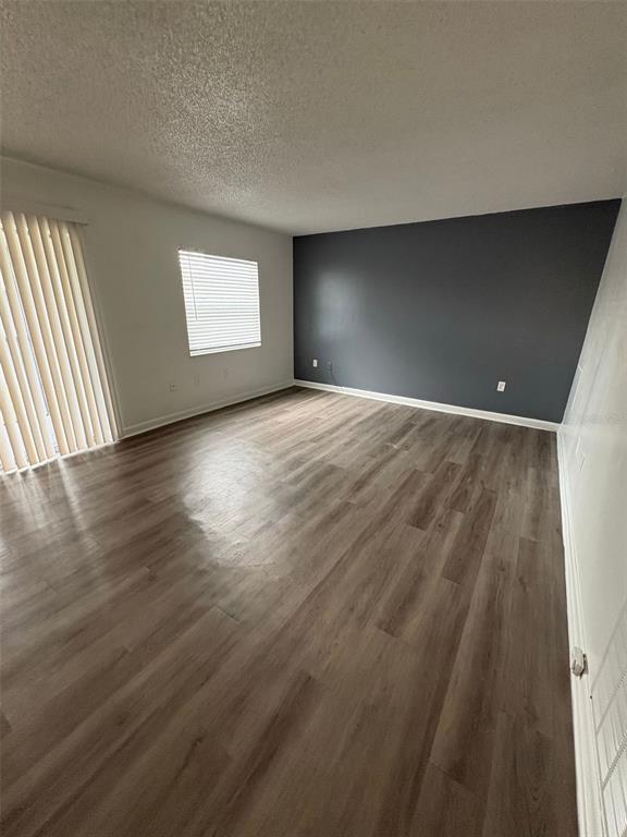 This virtually staged living room features a sectional sofa, a round coffee table, and dark flooring — 2523 N ALAFAYA TRAIL UNIT 42, ORLANDO, FL