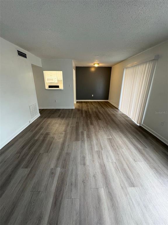 An empty living room features wood-look flooring, a dark accent wall, and vertical window blinds — 2523 N ALAFAYA TRAIL UNIT 42, ORLANDO, FL