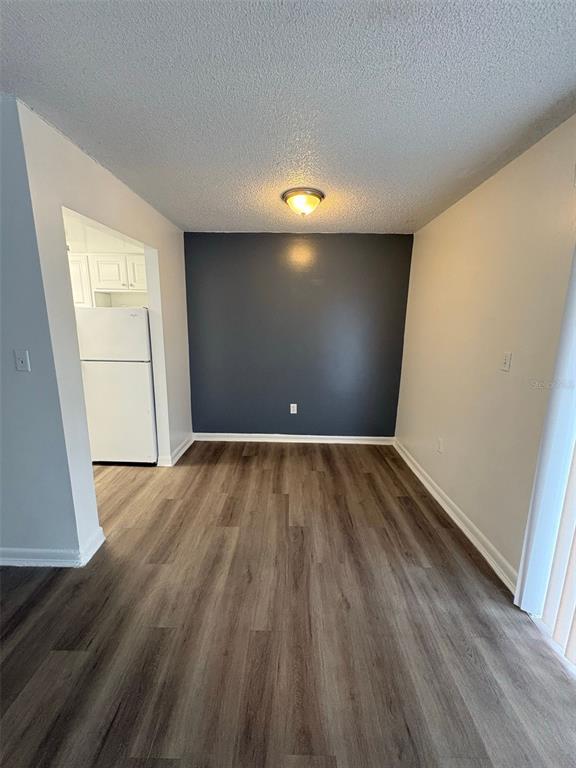 An empty living room features wood-look flooring, a dark accent wall, and sliding glass doors — 2523 N ALAFAYA TRAIL UNIT 42, ORLANDO, FL