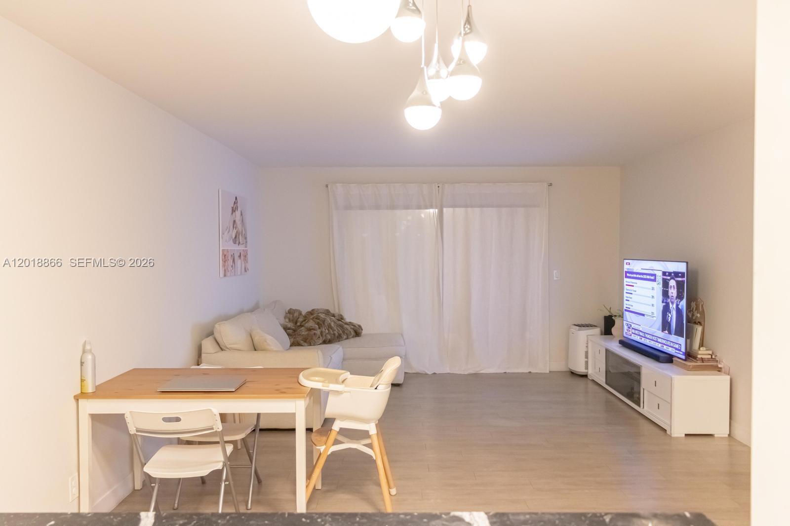 A living room features a dining table, a sectional sofa, and a television console — 2200 S Cypress Bend Dr # 204, Pompano Beach FL 33069, POMPANO BEACH, FL