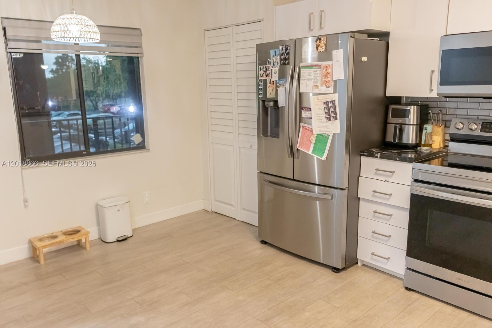 A kitchen features stainless steel appliances, white cabinetry, and light wood-look flooring — 2200 S Cypress Bend Dr # 204, Pompano Beach FL 33069, POMPANO BEACH, FL