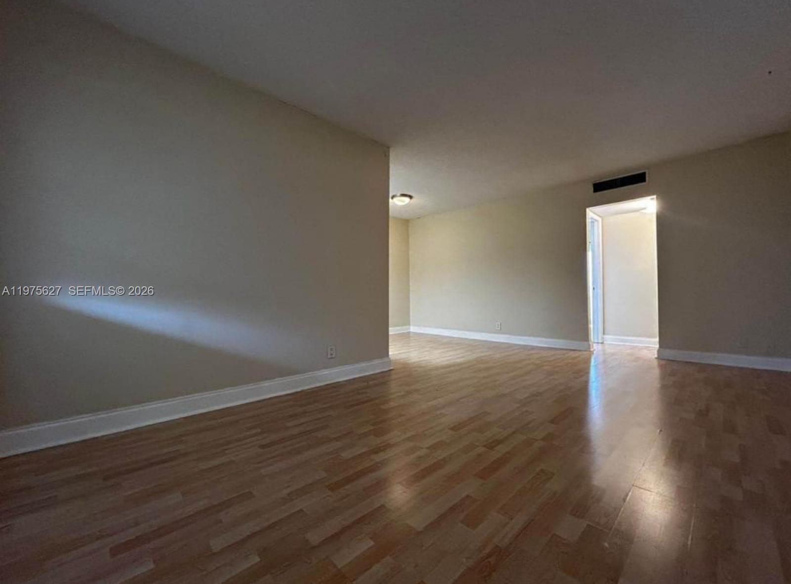 An empty room features light-colored walls, wood-look flooring, and a doorway leading to another space — 1100 NE 1st Ct # 312, Hallandale Beach FL 33009, HALLANDALE BEACH, FL