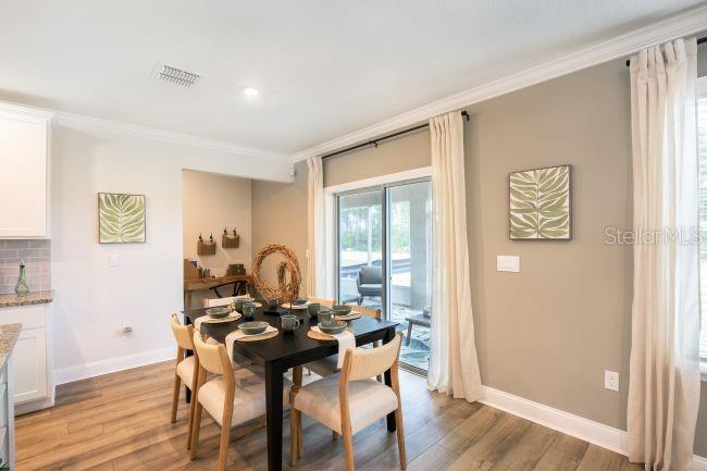 A dining area features a black table with four chairs, wood flooring, and sliding glass doors — 8087 SW 9TH LANE, GAINESVILLE, FL