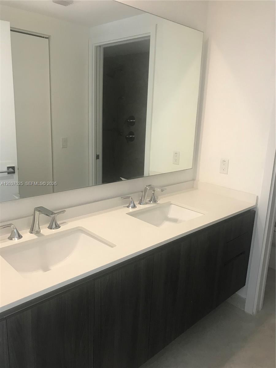 A modern double-sink bathroom vanity features dark wood cabinetry and a white countertop — 488 NE 18th St # 3102, Miami FL 33132, MIAMI, FL