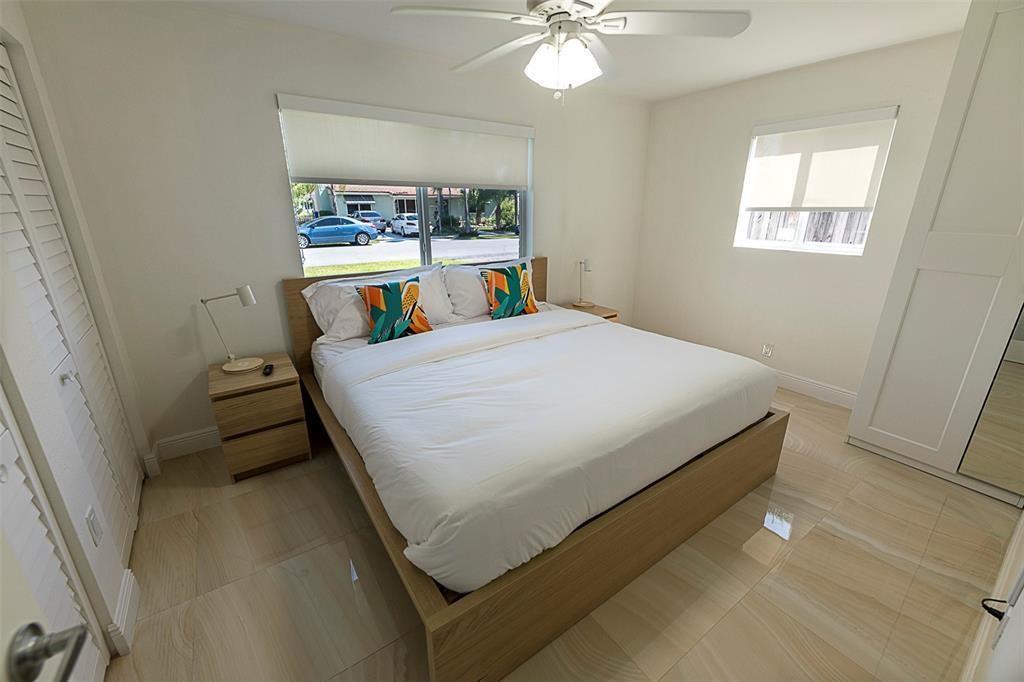 A bedroom features a platform bed, light wood-look tile flooring, and a ceiling fan — 1162 Hayes Street, Hollywood FL 33019, HOLLYWOOD, FL