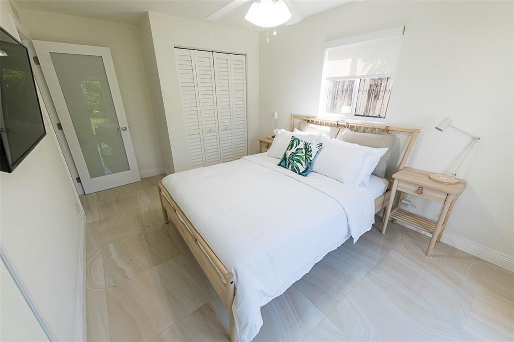A bedroom features a light wood bed frame, white bedding, tile flooring, and a closet — 1162 Hayes Street, Hollywood FL 33019, HOLLYWOOD, FL