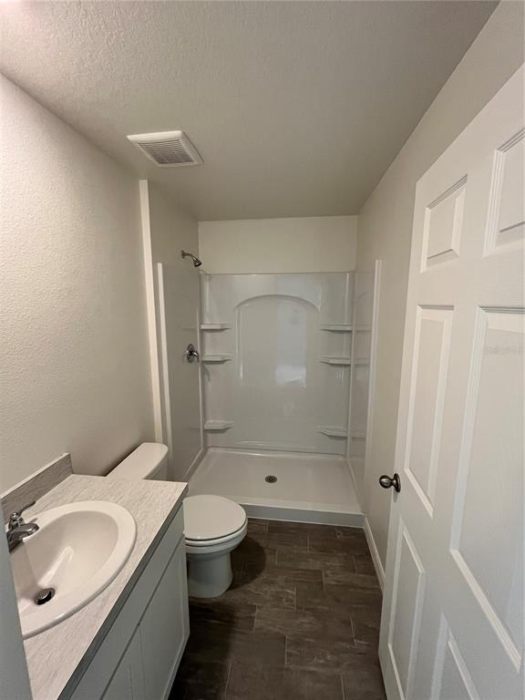 A bathroom features a vanity with a sink, a toilet, and a walk-in shower stall — 10540 YEAGER AVENUE, HASTINGS, FL