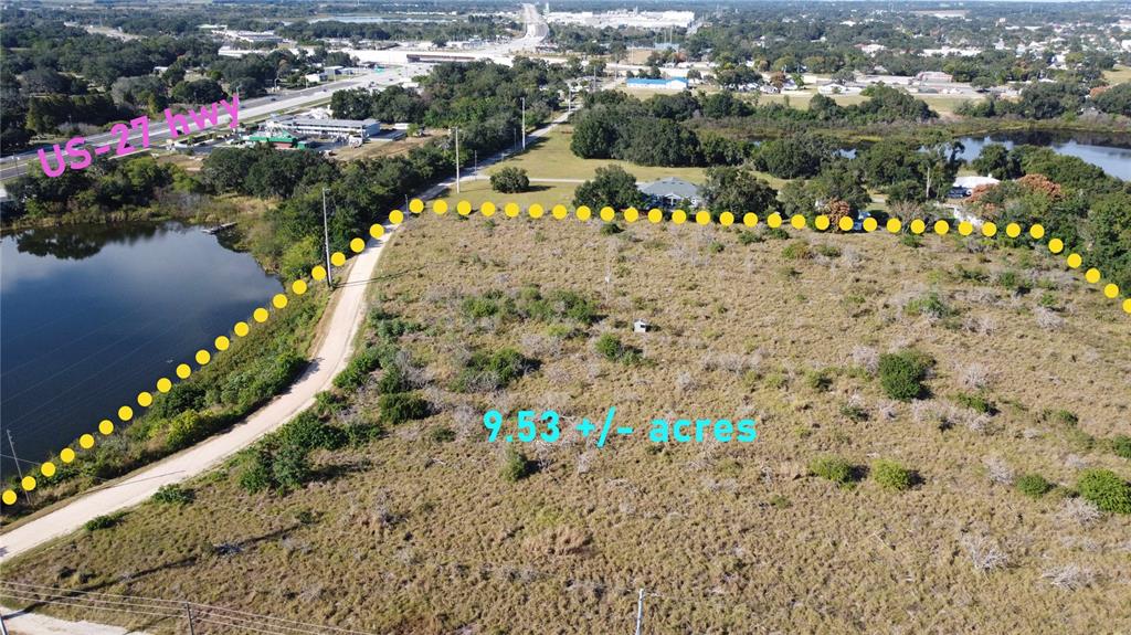 An aerial view shows a large, undeveloped grassy lot bordered by a road and water — 600 GROVE AVENUE, LAKE WALES, FL