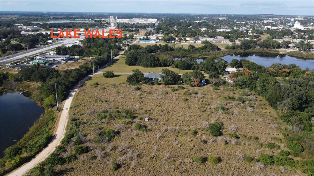 An aerial view shows a large, undeveloped grassy lot next to a lake and road — 600 GROVE AVENUE, LAKE WALES, FL
