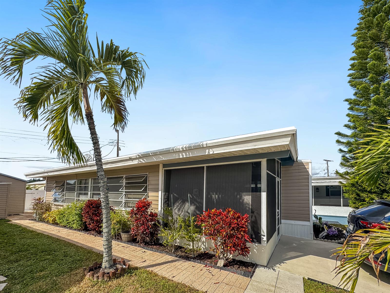A single-story house with a screened-in porch, a palm tree, and landscaping along a walkway — 14553 Elmhurst Drive, Delray Beach FL 33445, DELRAY BEACH, FL