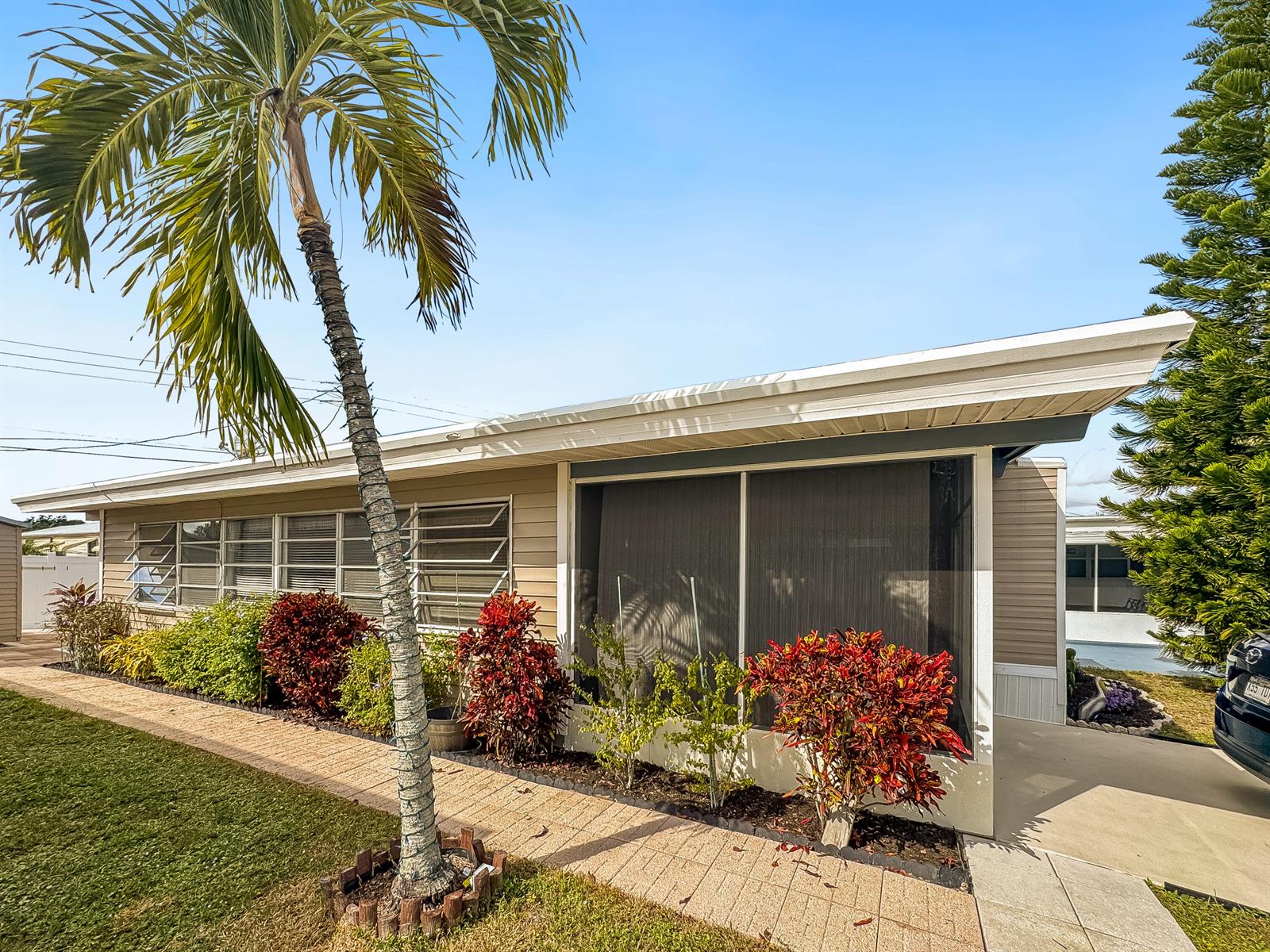 A single-story house with a screened porch, a palm tree, and landscaping under a blue sky — 14553 Elmhurst Drive, Delray Beach FL 33445, DELRAY BEACH, FL