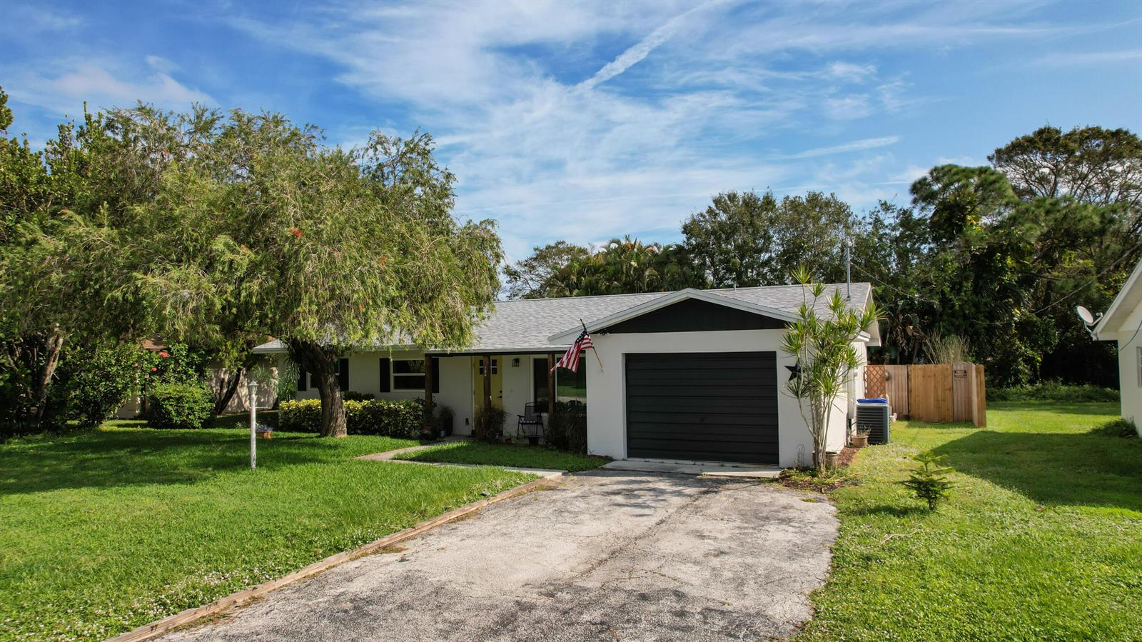 A single-story house with a dark garage door, a concrete driveway, and a large tree — 186 23rd Avenue, Vero Beach FL 32962, VERO BEACH, FL