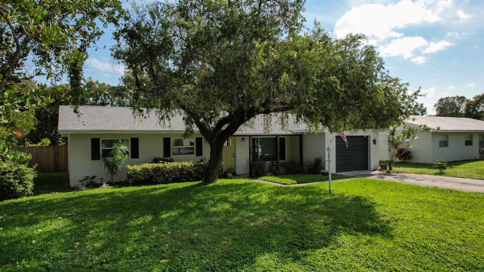 A single-story house with a white exterior, a dark garage door, and a large front tree — 186 23rd Avenue, Vero Beach FL 32962, VERO BEACH, FL