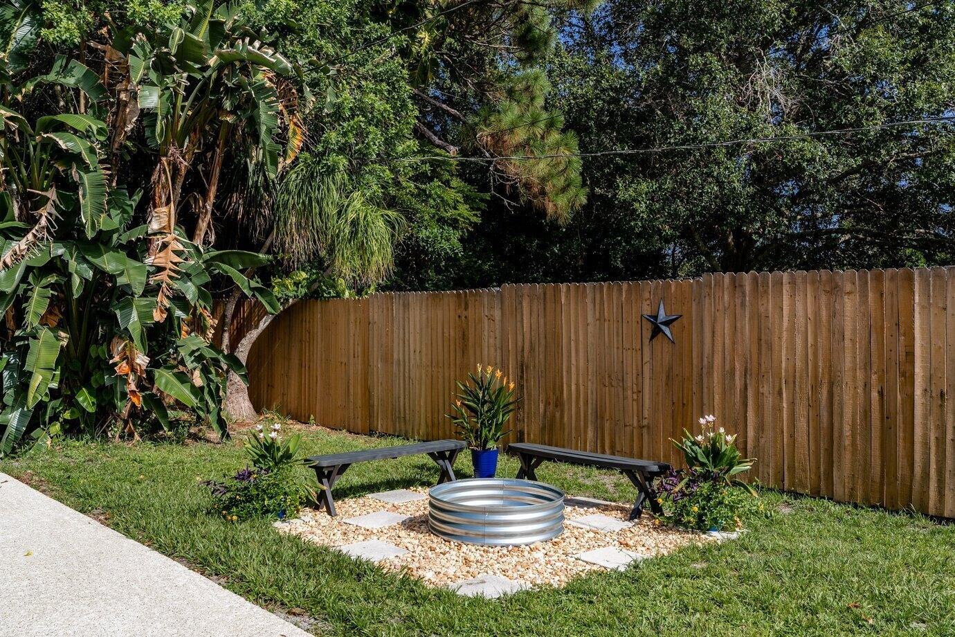 A backyard fire pit area features a metal ring, two benches, and potted plants — 186 23rd Avenue, Vero Beach FL 32962, VERO BEACH, FL