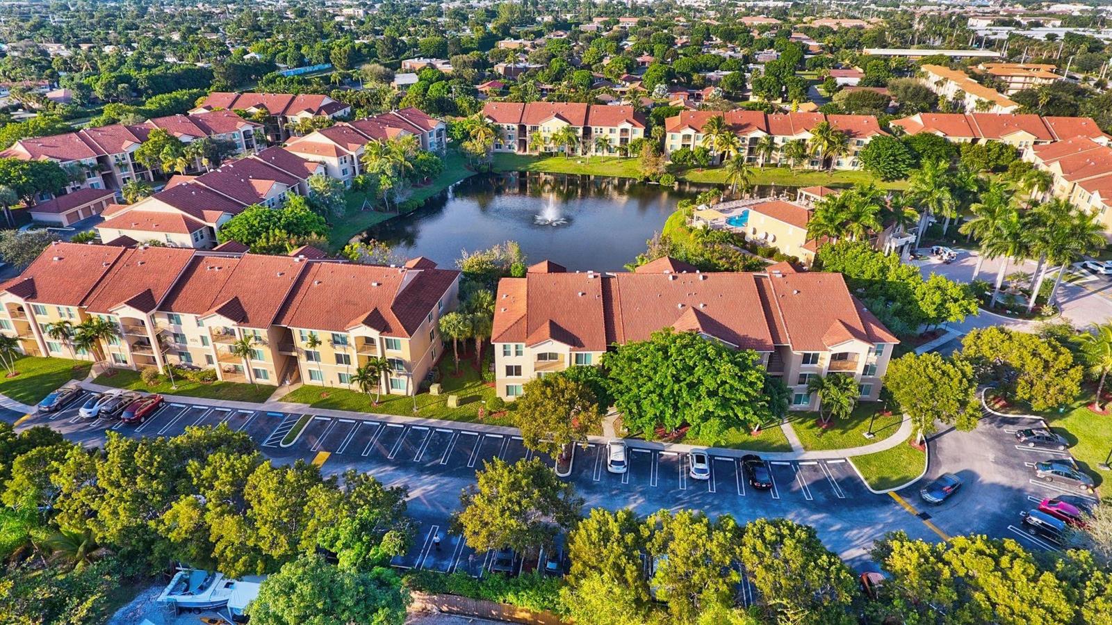 Aerial view of a multi-story apartment complex with red tile roofs surrounding a central pond — 310 Villa Circle # 310, Boynton Beach FL 33435, BOYNTON BEACH, FL