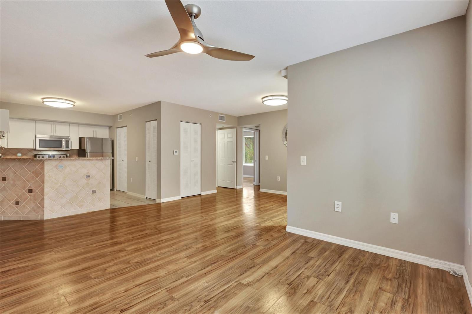 An open-concept living area features wood-look flooring, a ceiling fan, and an adjacent kitchen — 310 Villa Circle # 310, Boynton Beach FL 33435, BOYNTON BEACH, FL