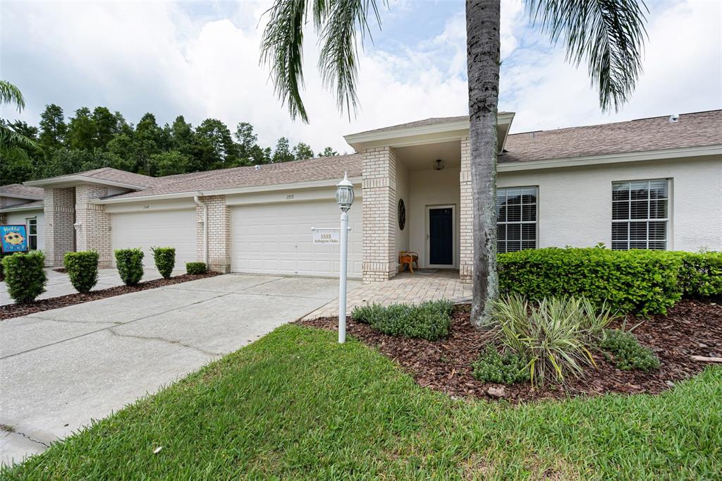 A single-story house with a two-car garage, brick accents, and a paved walkway — 1553 ARLINGTON OAKS COURT, NEW PORT RICHEY, FL