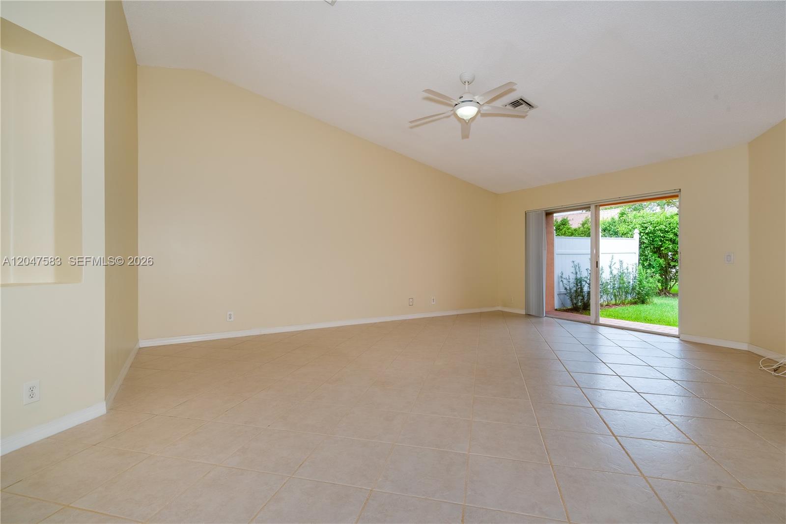 An empty living room features beige tile flooring, vaulted ceilings, and a sliding glass door — 4152 Pine Ridge Ln # 0, Weston FL 33331, WESTON, FL