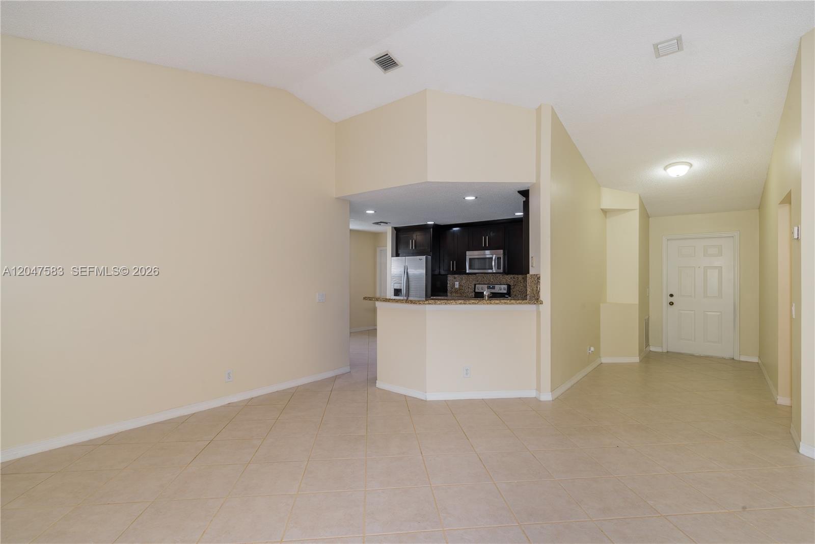 An open-concept living area features tile flooring, a kitchen with dark cabinets, and vaulted ceilings — 4152 Pine Ridge Ln # 0, Weston FL 33331, WESTON, FL