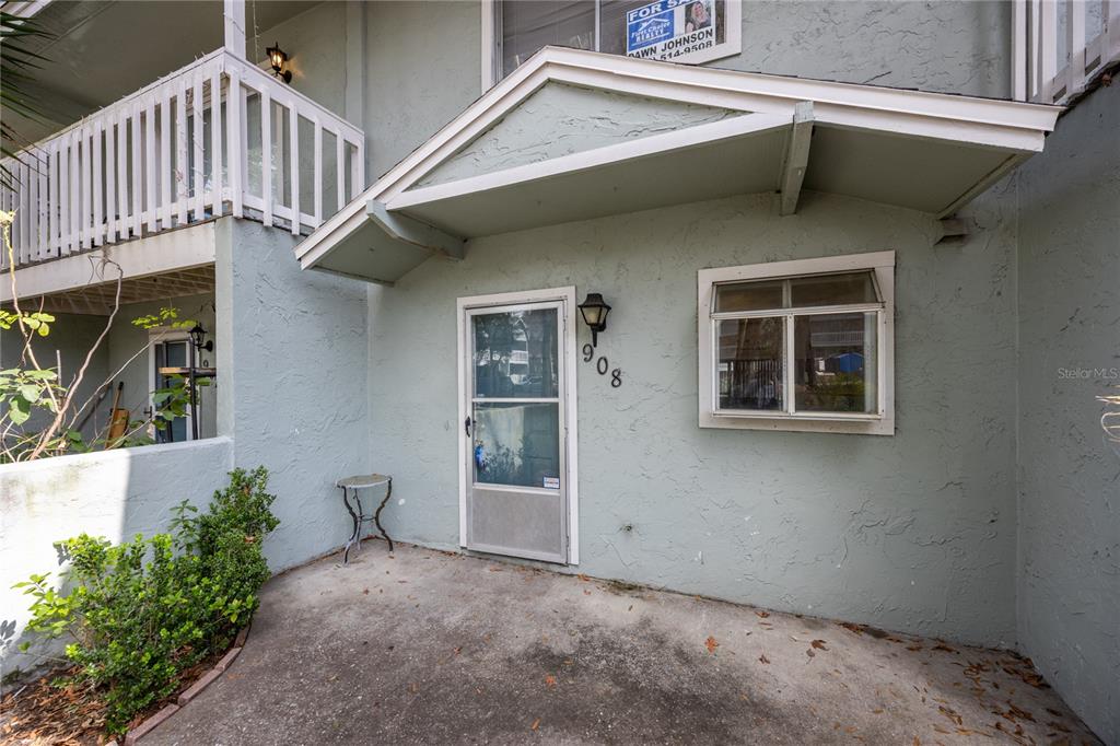 The exterior of a light green condo unit features a concrete patio and white railing — 4411 SW 34TH STREET UNIT 908, GAINESVILLE, FL