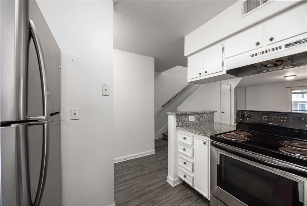 A kitchen features stainless steel appliances, white cabinets, granite countertops, and wood-look flooring — 4411 SW 34TH STREET UNIT 908, GAINESVILLE, FL
