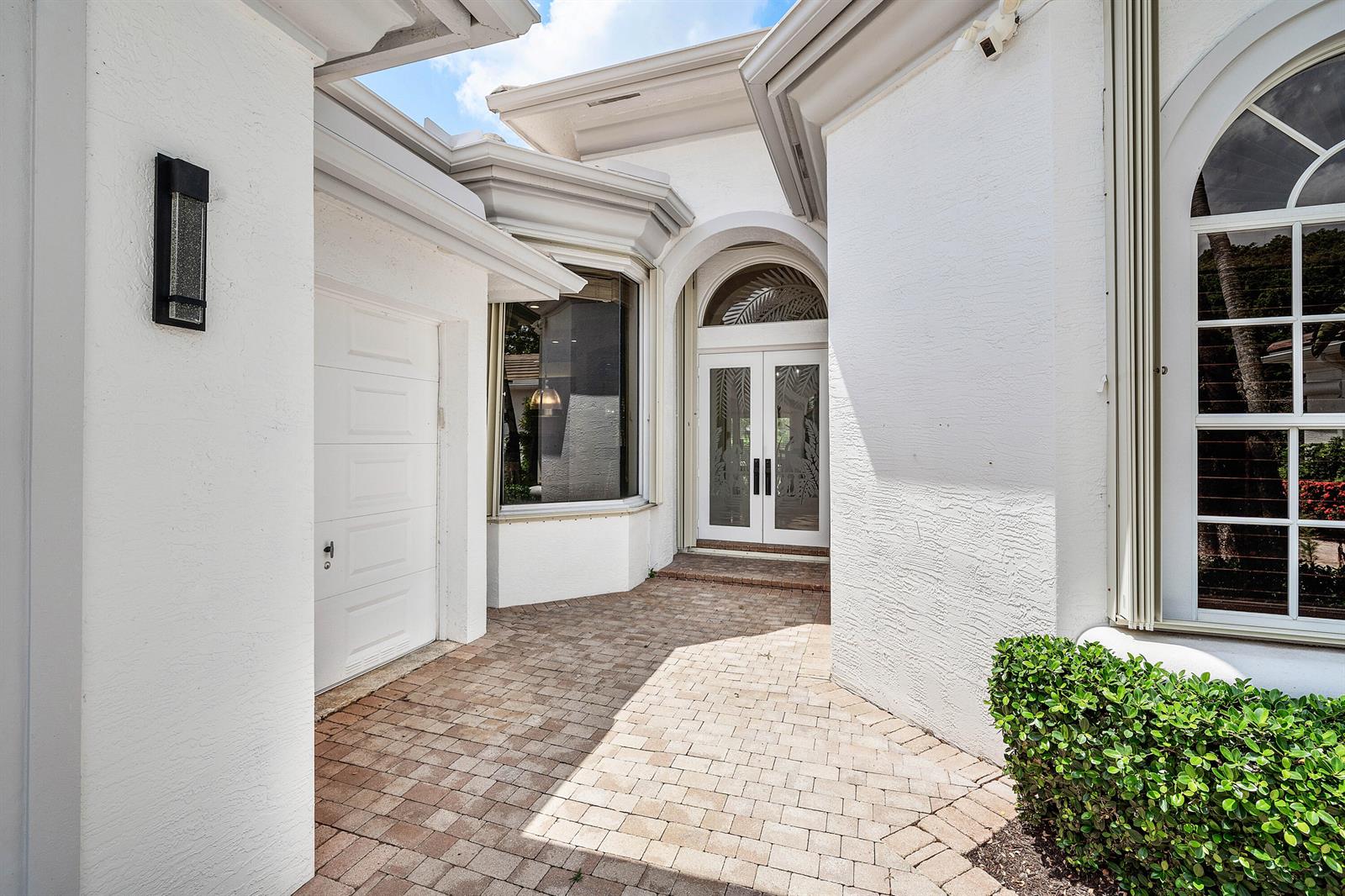 A paved walkway leads to the white double front doors of a stucco house exterior — 7917 Villa D Este Way, Delray Beach FL 33446, DELRAY BEACH, FL