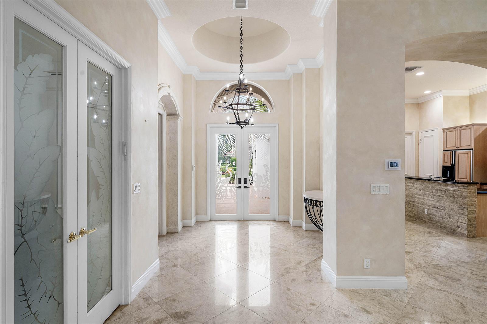 A bright foyer features a domed ceiling, a chandelier, and light-colored tile flooring — 7917 Villa D Este Way, Delray Beach FL 33446, DELRAY BEACH, FL