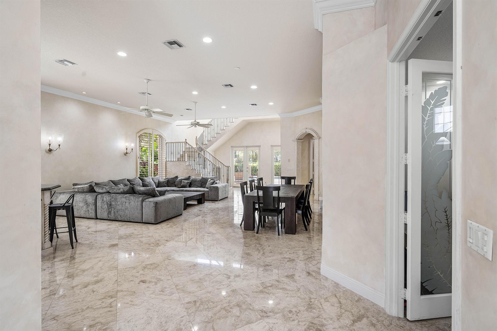 A spacious living and dining area features polished marble floors, a large sectional, and stairs — 7917 Villa D Este Way, Delray Beach FL 33446, DELRAY BEACH, FL