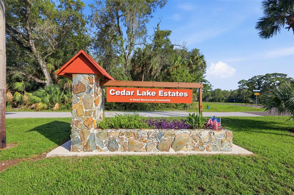 A stone monument sign with a red roof displays the name Cedar Lake Estates — 11100 W CEDAR LAKE DRIVE, CRYSTAL RIVER, FL