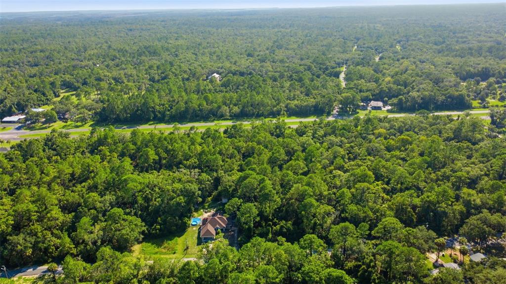 An aerial view shows a house with a pool surrounded by dense forest and roads — 11100 W CEDAR LAKE DRIVE, CRYSTAL RIVER, FL