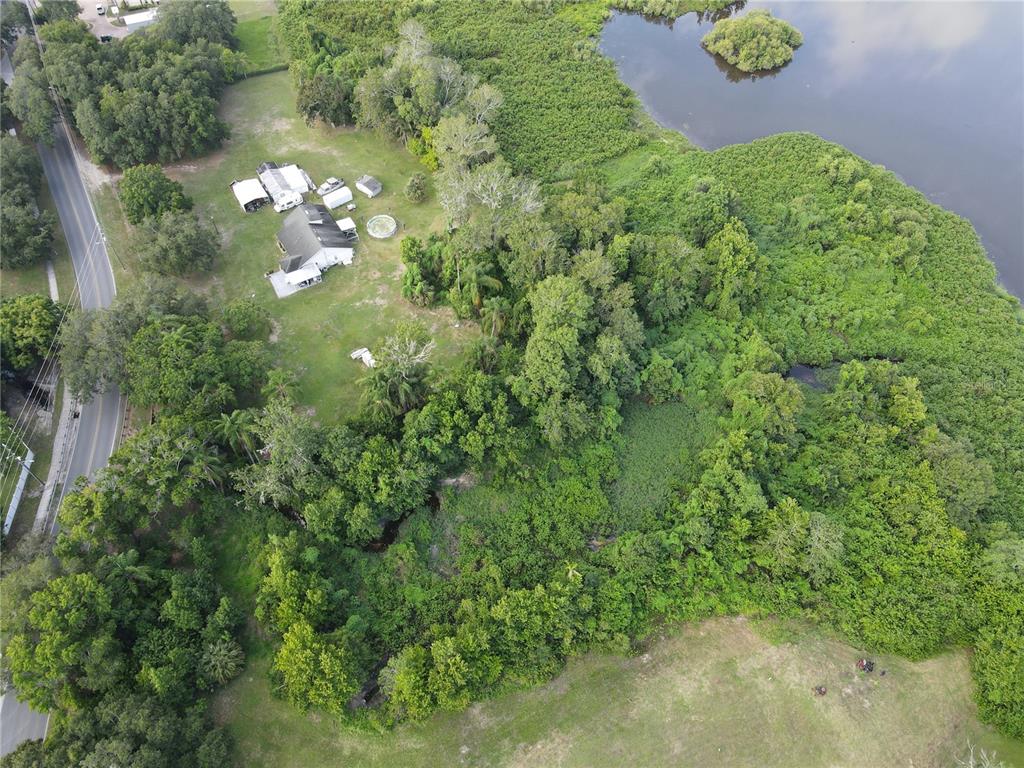 An aerial view shows a house with outbuildings on a large, wooded lot near water — 1401 N FULLERS CROSS ROAD, WINTER GARDEN, FL