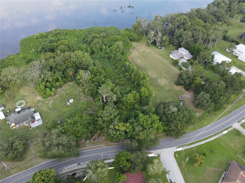 An aerial view shows a large, wooded waterfront lot situated between two residential properties — 1401 N FULLERS CROSS ROAD, WINTER GARDEN, FL