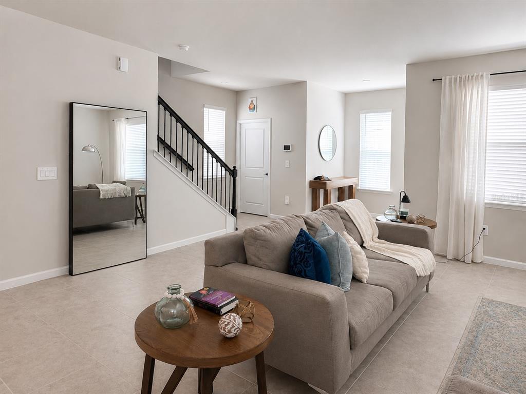 A living room features a grey sofa, a round wooden coffee table, and a large mirror — 3974 GREAT SMOKEY WAY, APOPKA, FL