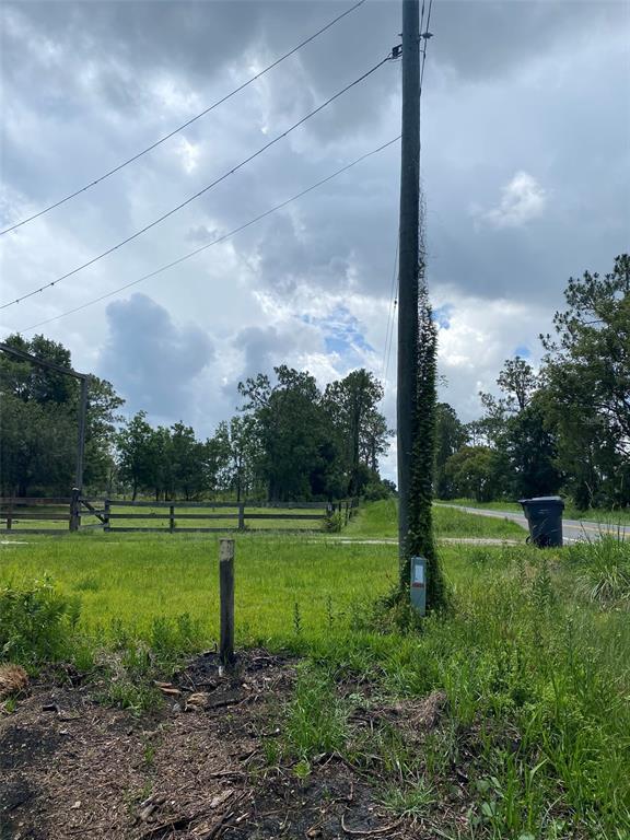 A utility pole stands in a grassy field next to a wooden fence and road — 2101 W FROSTPROOF ROAD, FROSTPROOF, FL