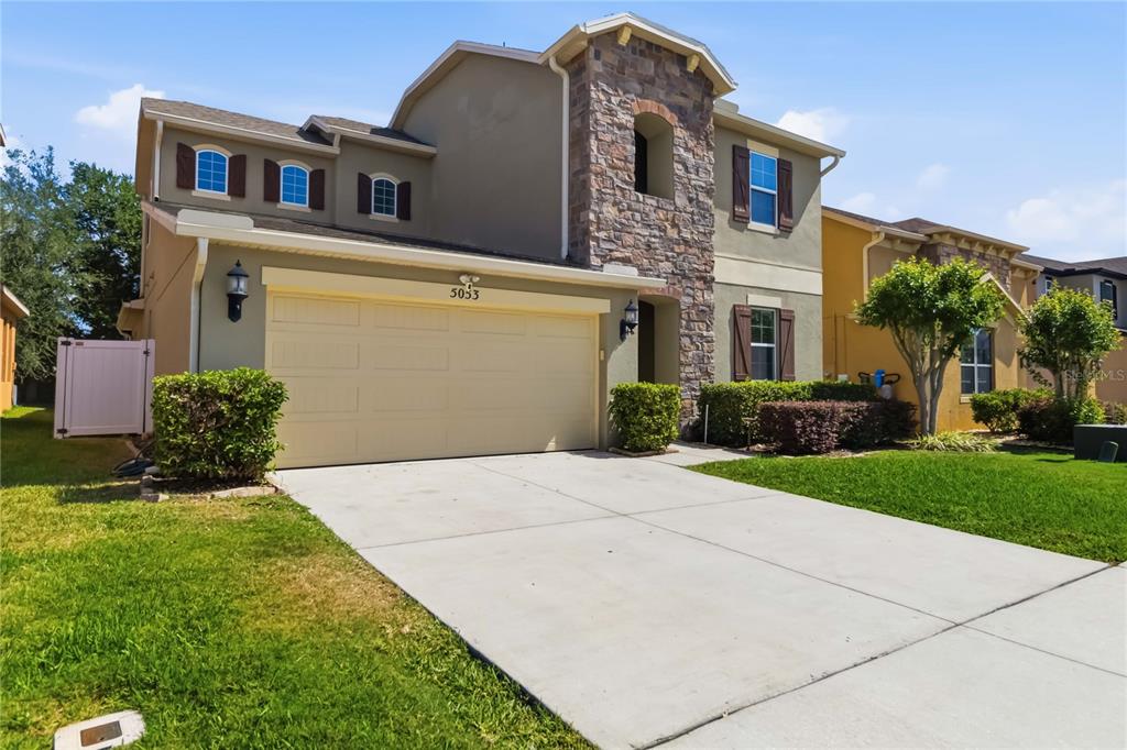 A two-story house with a stone facade, beige stucco, and a two-car garage — 5053 TORCHWOOD DRIVE, MINNEOLA, FL